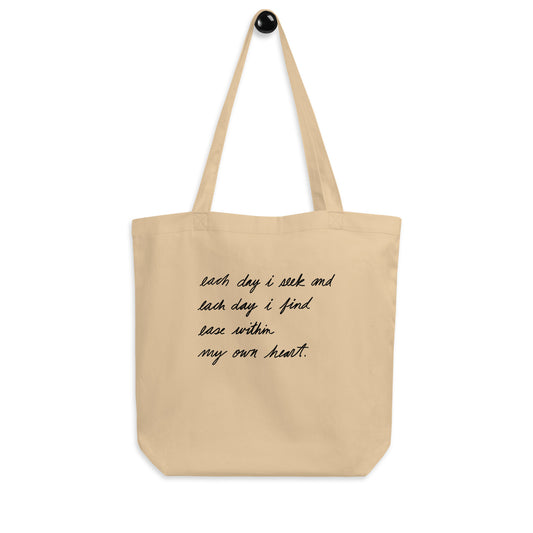 organic cotton tote bag in natural oyster with handwritten poem that reads: each day i seek and each day i find ease within my own heart. written by ashton guy.