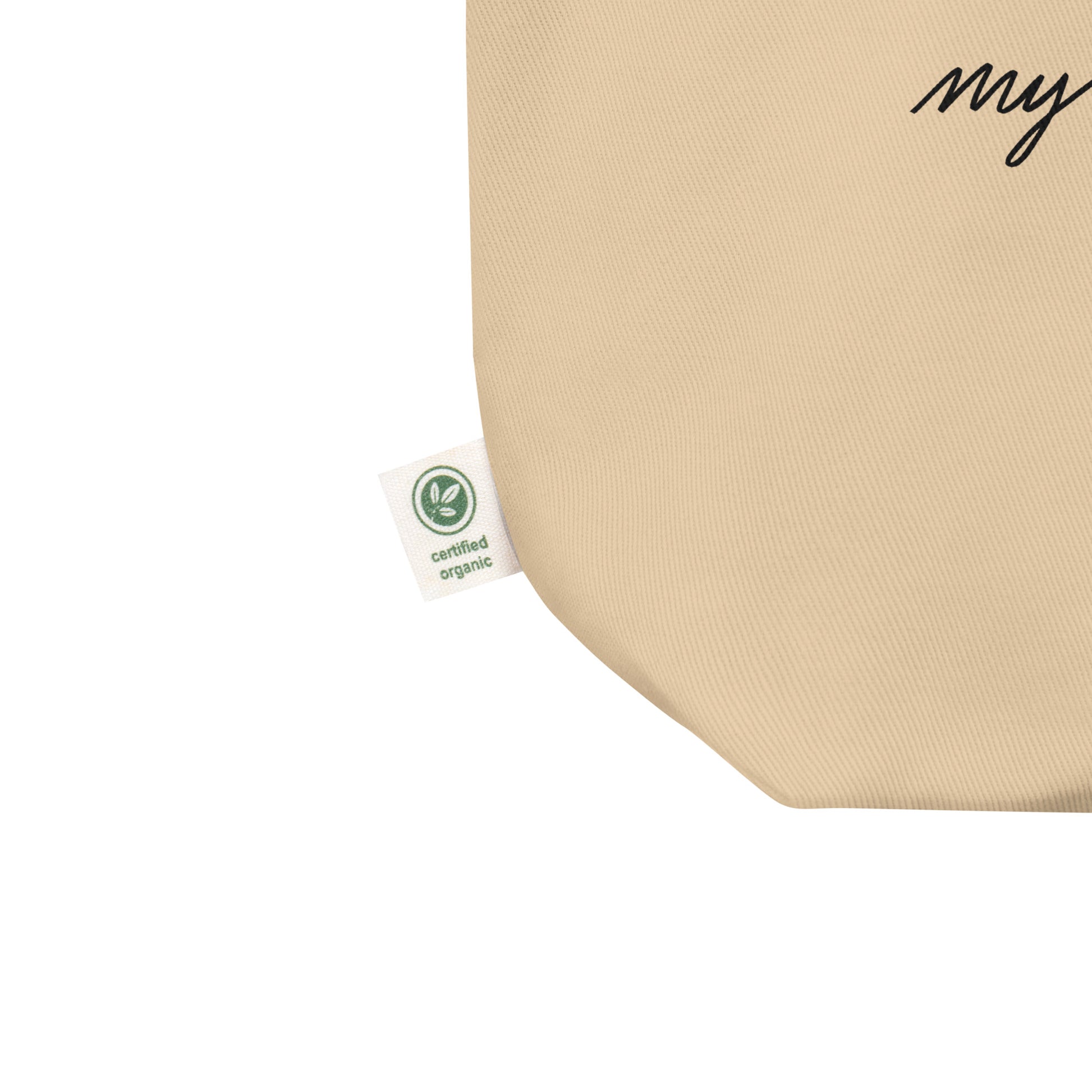 close up view of rounded bottom edge of organic cotton tote bag displaying its small certified organic tag.