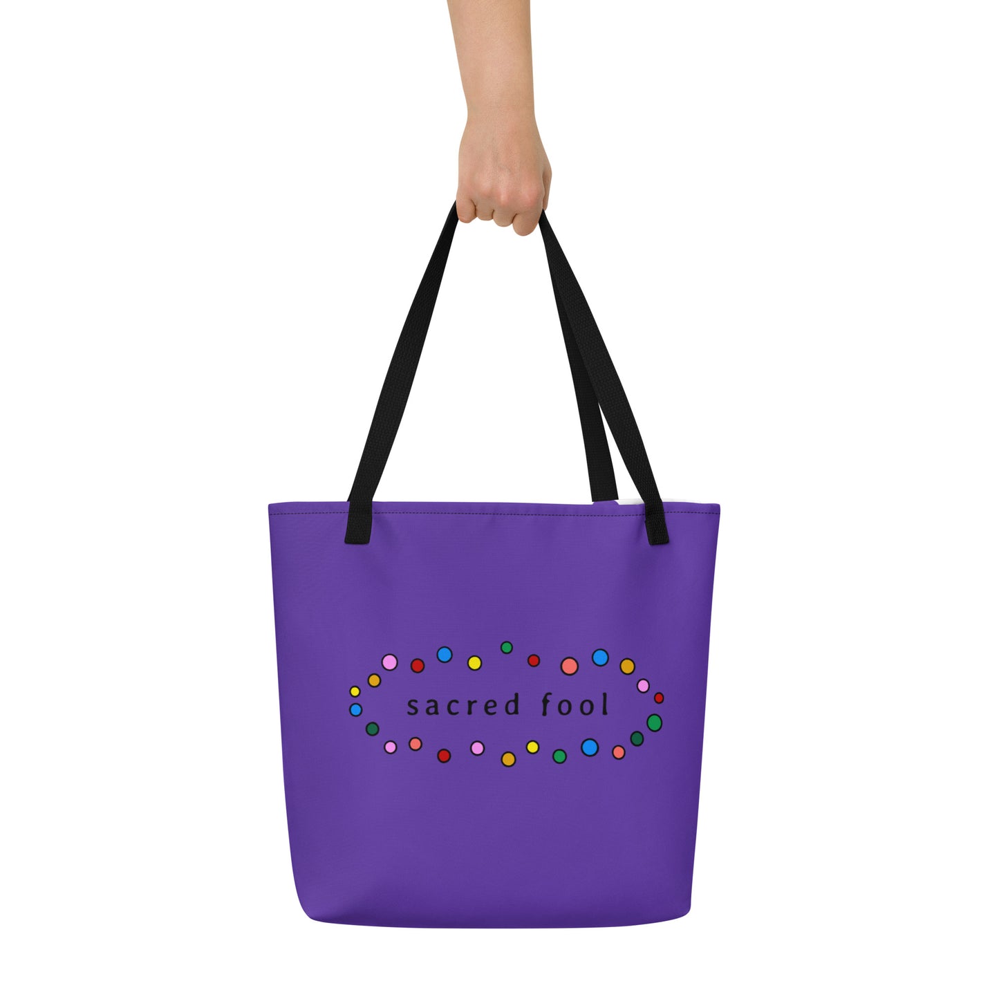 back view of purple shopping tote bag features the sacred fool logo in black surrounded by a waving encircling of polka bubbles in red, yellow, yellow ochre, neon salmon, grass green, evergreen, sky blue, and bubblegum pink outlined in black.